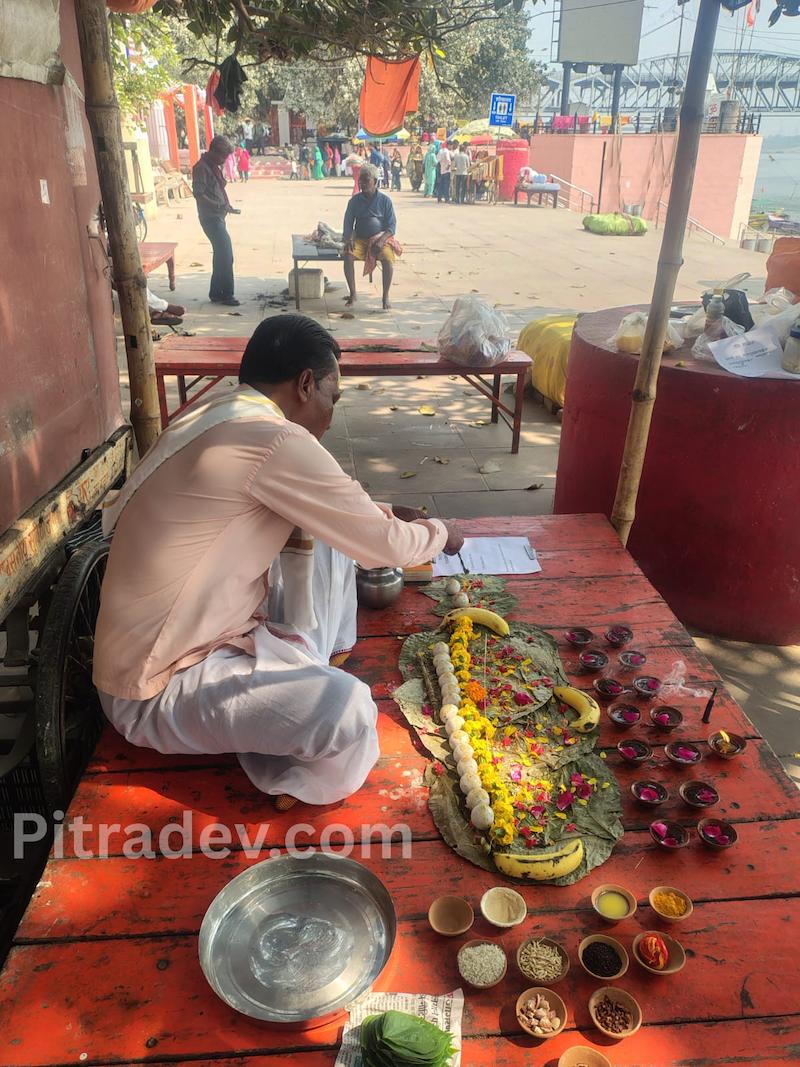 Priest performing online pind daan in Varanasi with ritual setup including pind, diya and offerings at ghat